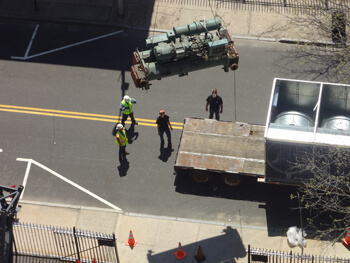 Four NEMSI technicians waiting at ground level for an HVAC unit to be lowered down during install.