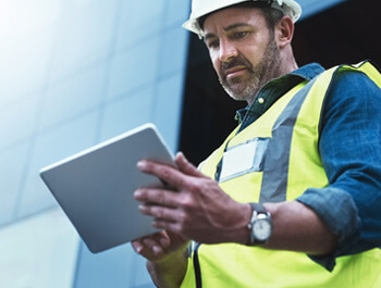 Technician looking at a computer tablet performing an energy audit.