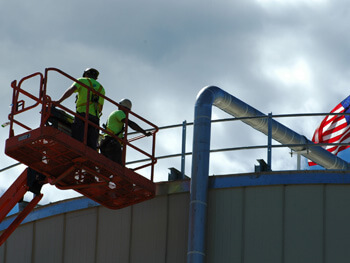 Two NEMSI project technicians on a lift at a construction site.