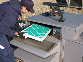 NEMSI technician changing an HVAC filter during preventive maintenance services.