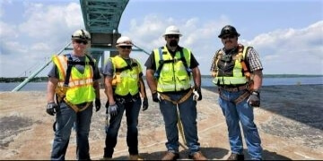 Four NEMSI employees wearing safety gear.